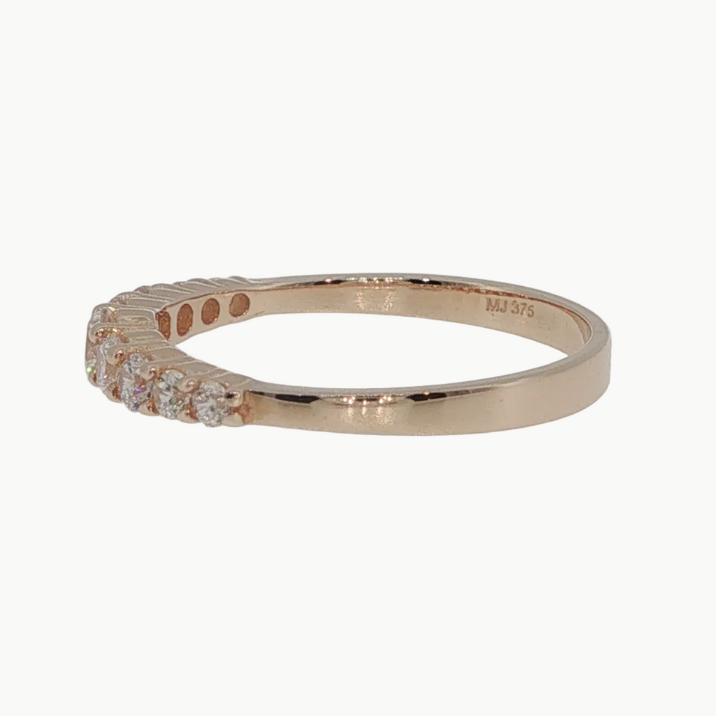 A rose gold ring with a row of small clear gemstones on the front, photographed on a clean white background.