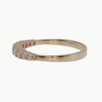 A rose gold ring with a row of small clear gemstones on the front, photographed on a clean white background.