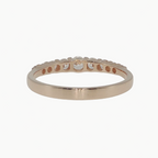 A rose gold eternity band ring with a row of small round-cut clear stones, photographed on a clean white reflective surface.