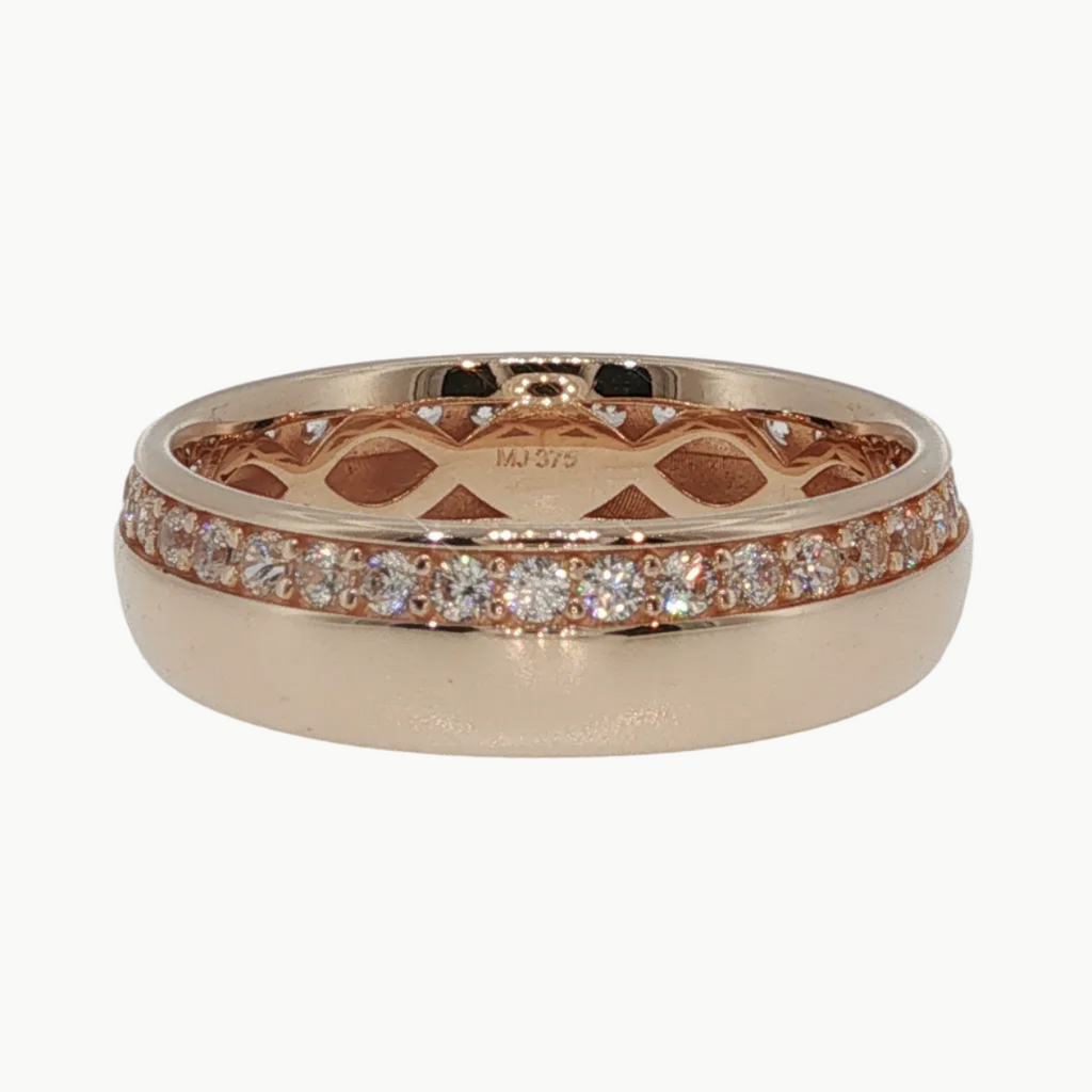 A rose gold eternity ring with a pavé diamond band and an openwork geometric pattern on the inner band, shown on a reflective white surface.