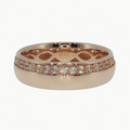 A rose gold eternity ring with a pavé diamond band and an openwork geometric pattern on the inner band, shown on a reflective white surface.