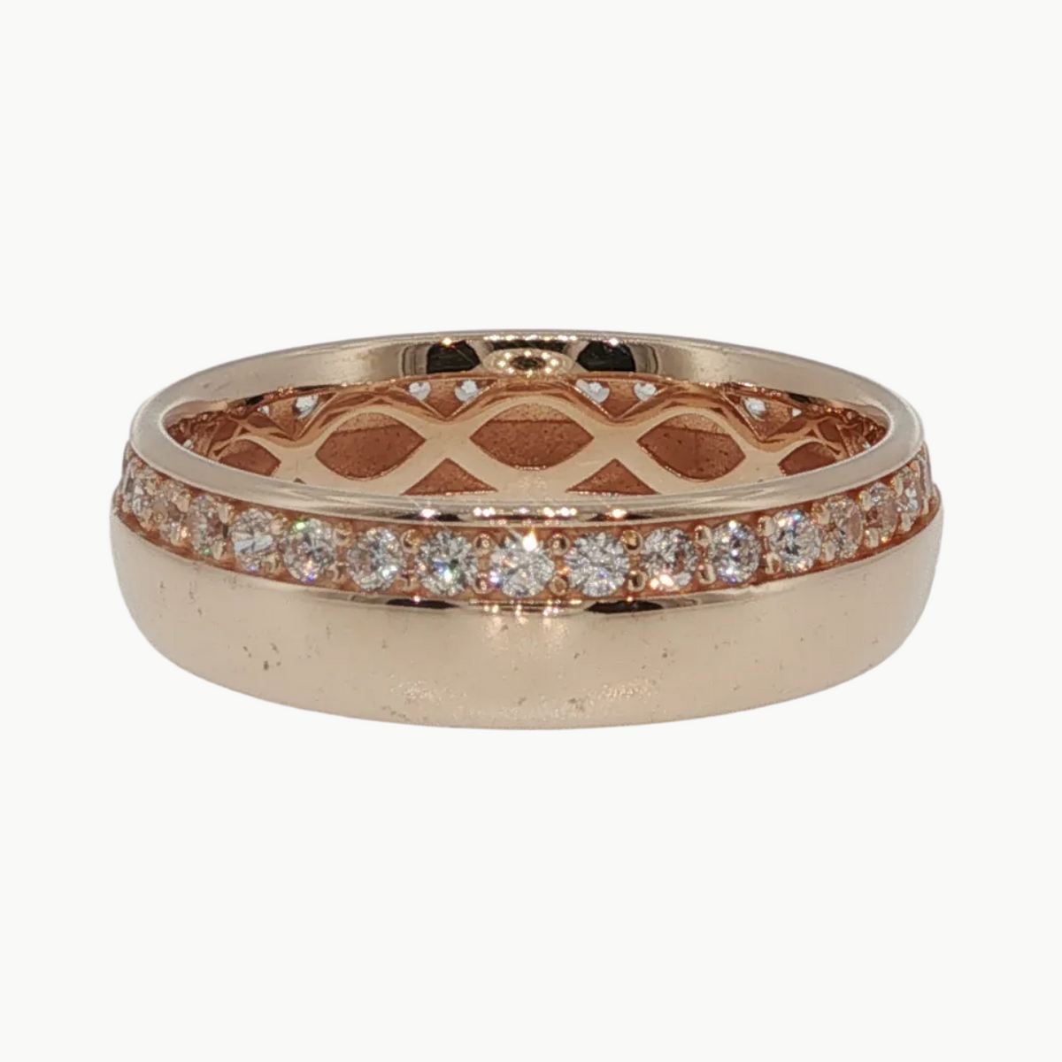 A rose gold band ring with a lattice pattern on the inside and a row of small clear stones along the outer edge, shown on a light gray reflective surface.