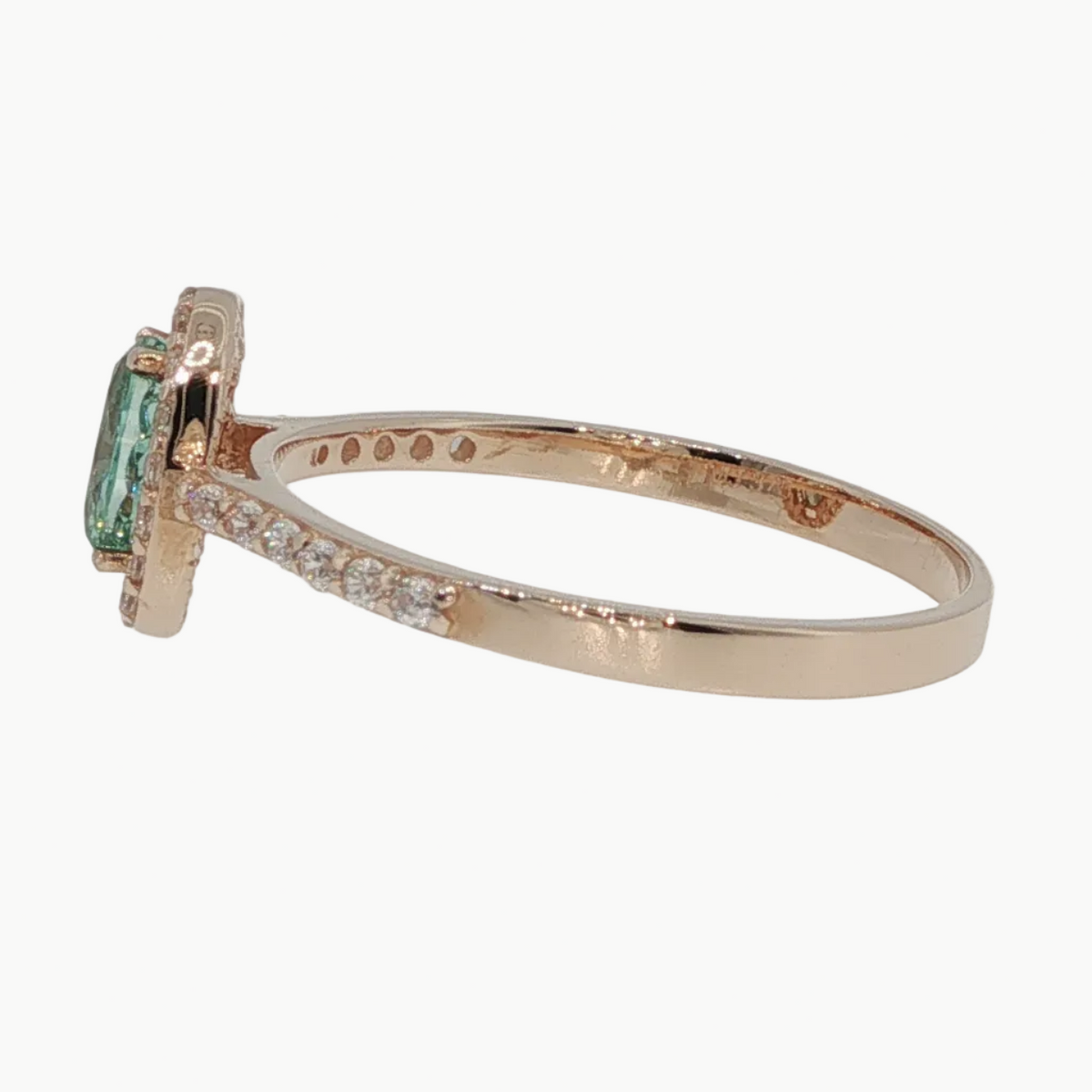 A rose gold ring featuring a rectangular green emerald-cut gemstone in a prong setting, with small pavé diamonds along the band, shown on a light gray reflective surface.