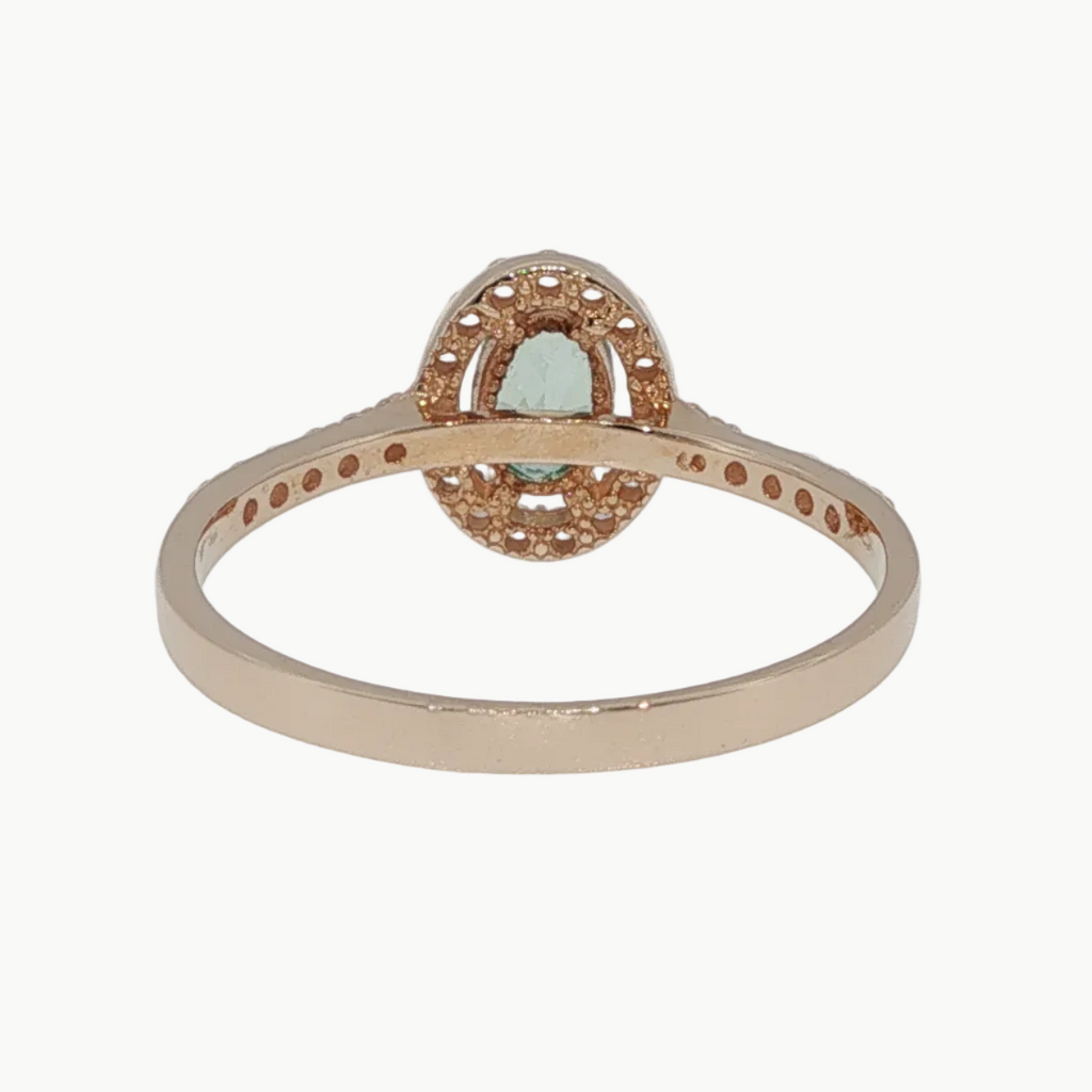 A rose gold ring with a central oval cluster of small clear stones and a marquise-cut green gemstone in the middle, shown on a light gray background.