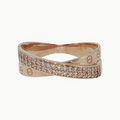 A rose gold ring with a twisted design, featuring one band paved with small clear stones and the other engraved with the brand name Cartier and its signature 'C' logo, set against a clean white background.
