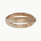 A rose gold wrap ring with a textured inner band, a smooth outer band featuring two screw-like details, and a pavé-set row of small clear stones on the side, shown on a light gray reflective surface.